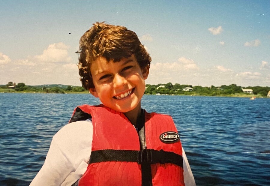 Luke as a kid on a boat with a lifejacket on